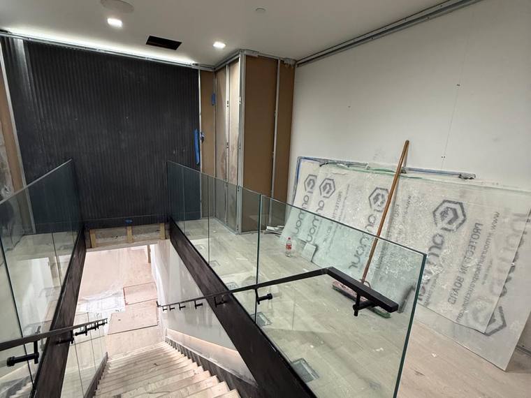 Finished glass guard on a commercial stair with a blackened steel stringer.