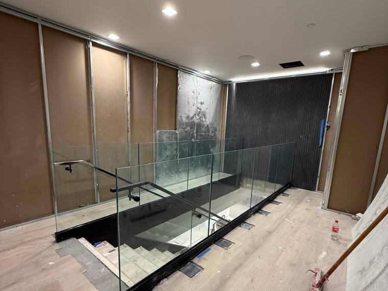 Glass guard seen from a landing above a commercial stair.