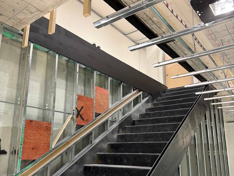 Steel stair in a building shell with trades working around it.