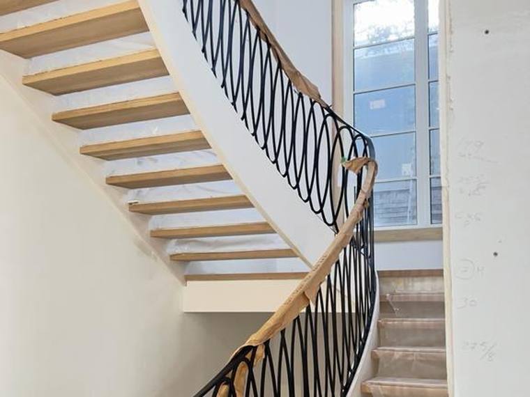 Curved staircase with iron balusters and a timber handrail.