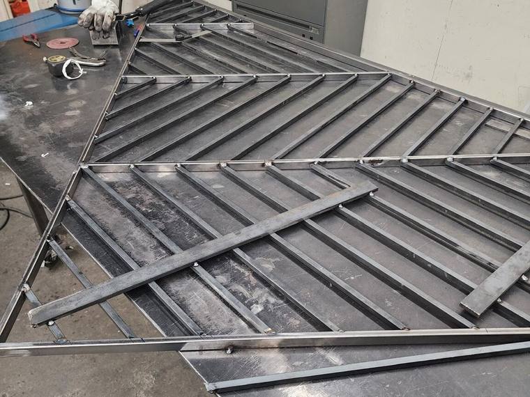 Herringbone steel railing panel being welded in the shop.