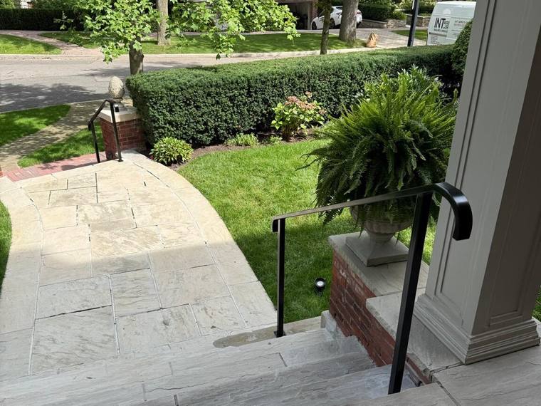 Black handrail on exterior stone steps.