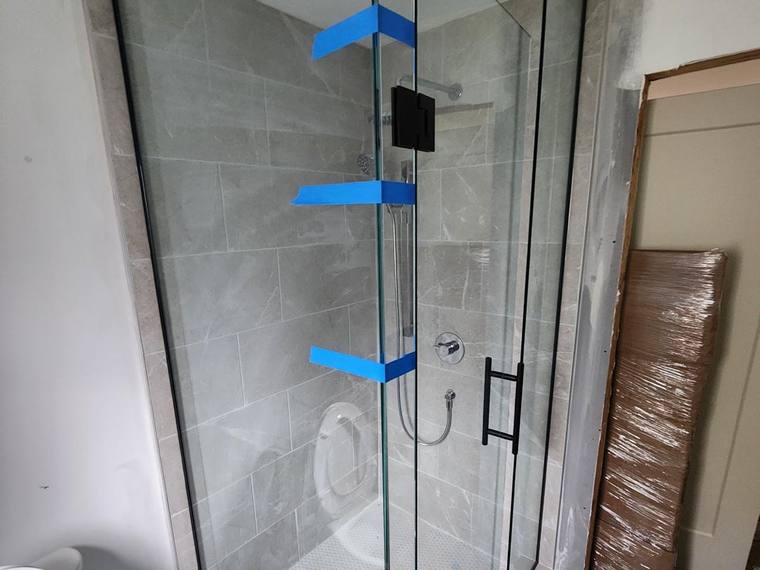 Frameless glass shower enclosure during installation.