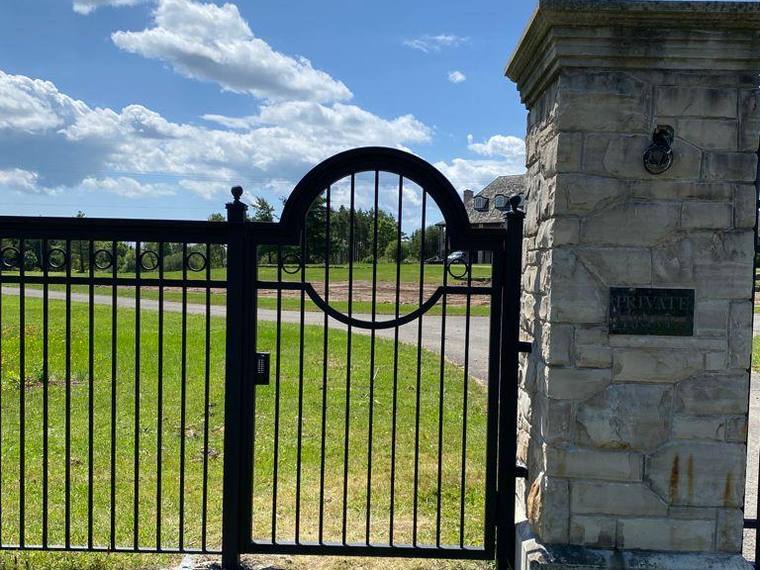 Iron pedestrian gate between stone pillars.