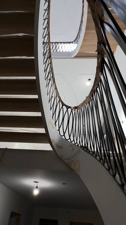 Curved wrought iron railing around an oval stair opening.