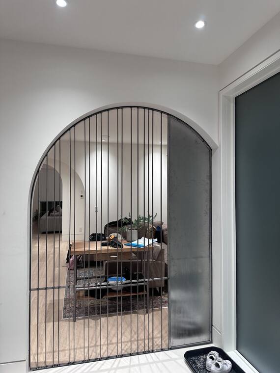 Arched iron screen between an entry and a living room.