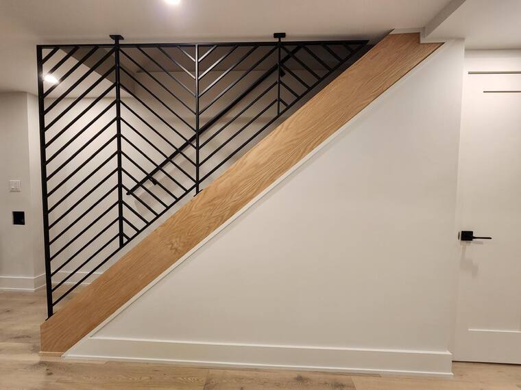 Herringbone steel railing against a white wall with an oak handrail.