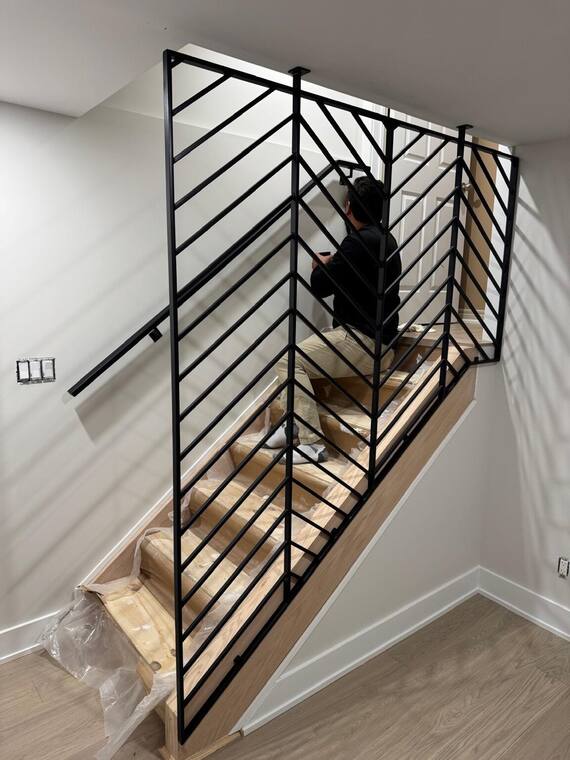 Fabricator fitting a herringbone steel railing on site.